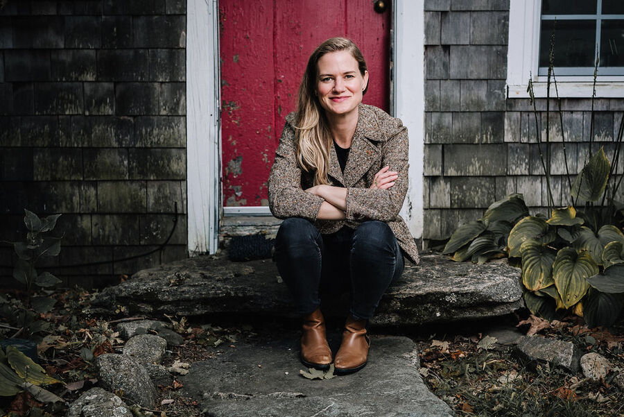 Emily sitting on a stone step in front of a red door.