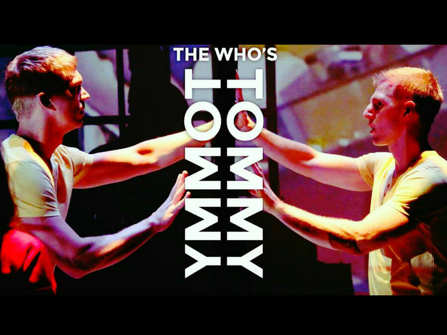 Two white actors with blond hair, both playing Tommy, stand facing each other with palms up, as mirror images. They wear matching yellow v-neck shirts, jeans, and black sneakers. The words “The Who’s Tommy” are superimposed in white text down the middle of the image, with Tommy’s name reflected upside down vertically as if split by a mirror.